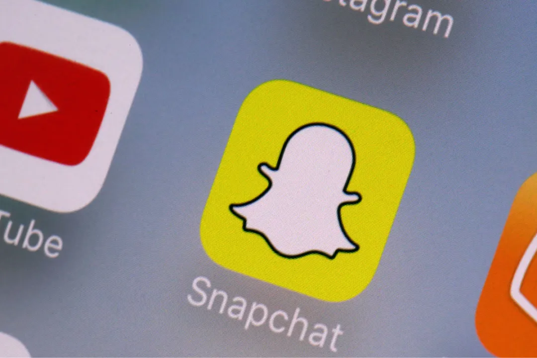 Snapchat app icon on a phone screen, beside YouTube and Instagram icons