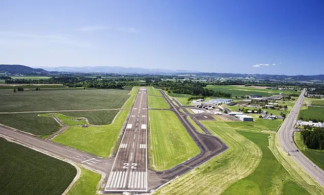 Aerial view of a rural airport runway marked 22 with surrounding farmland and hangars.