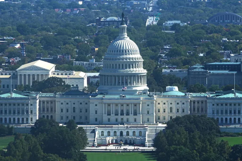 Aerial view of the U.S. Capitol dome and building surrounded by green trees.