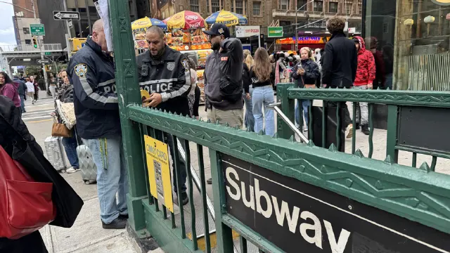 Officers in NYPD-style jackets stand near a green subway entrance marked Subway on a busy city street.
