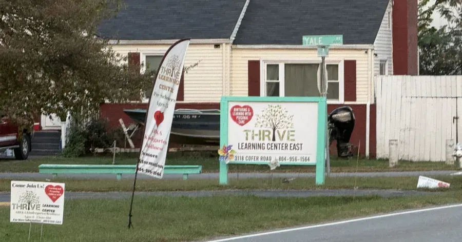 Thrive Learning Center East daycare sign, feather banner and yard signs in front of a residential house.