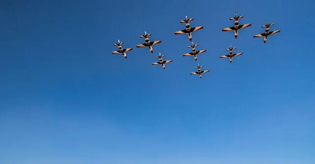 Formation of military jets flying against a clear blue sky.