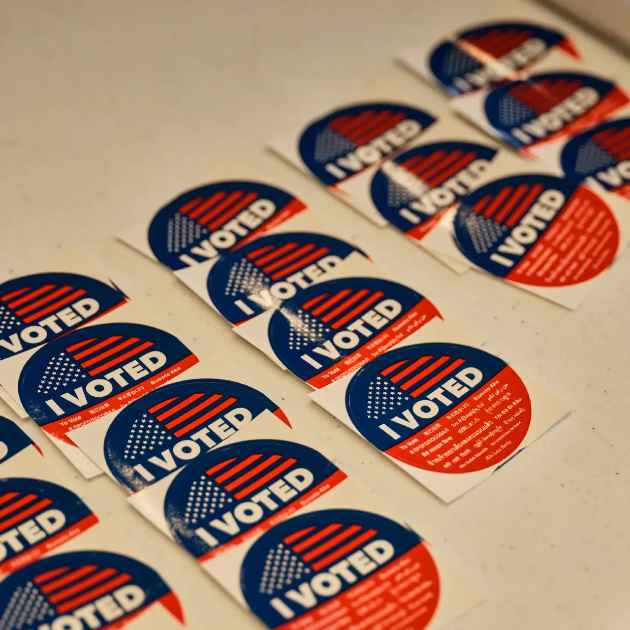Rows of red, white and blue "I VOTED" stickers on a light surface