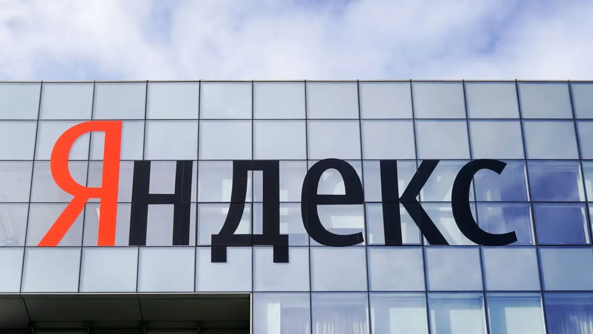 Yandex name sign on a glass-facade building under a cloudy sky.