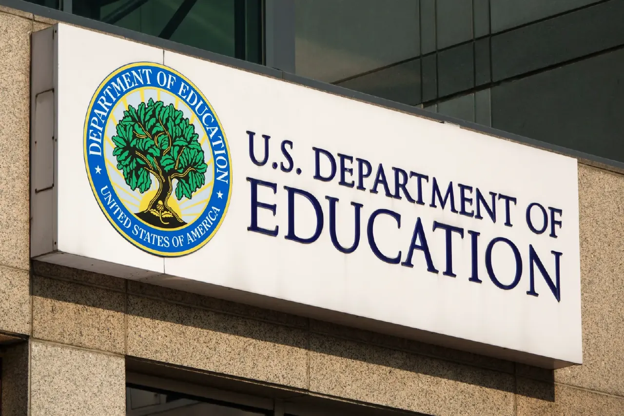 Exterior building sign with the U.S. Department of Education seal and name on granite facade.