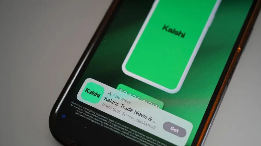 Smartphone screen showing Kalshi app logo, green app listing and trade-now button.