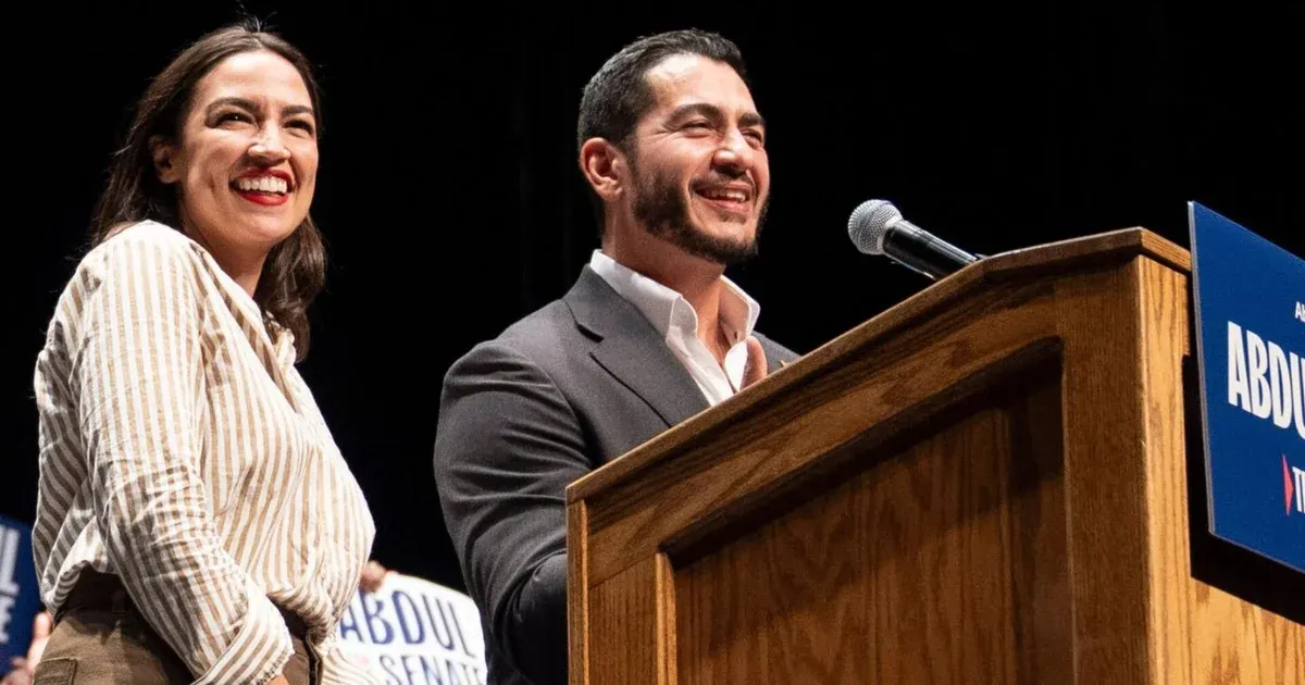 Two smiling people beside a wooden podium with a campaign sign reading Abdul Senate.