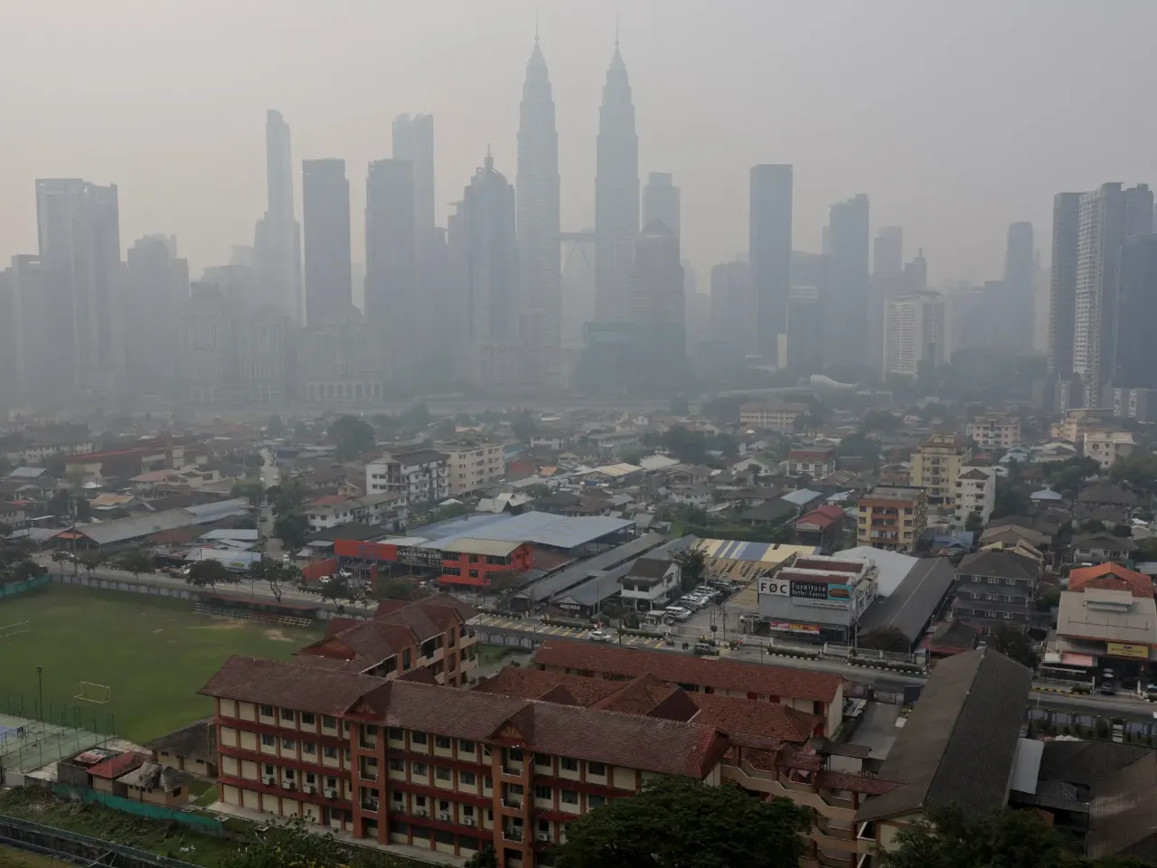 Hazy city skyline with towers and low-rise buildings shrouded in smoky haze