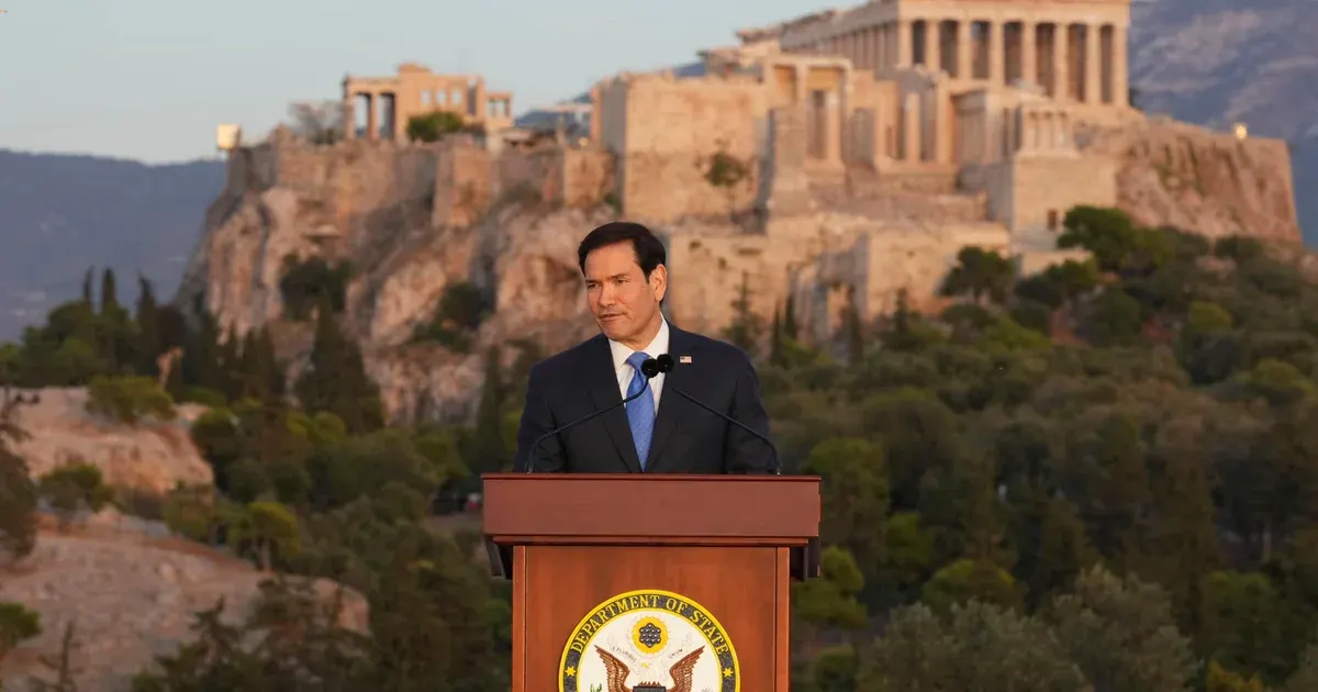Person speaking at podium with State Department seal, Acropolis visible behind.