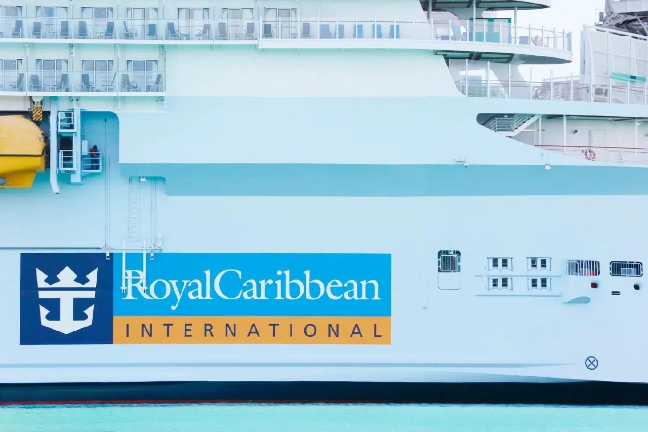 Side of a white cruise ship with Royal Caribbean International logo at waterline.