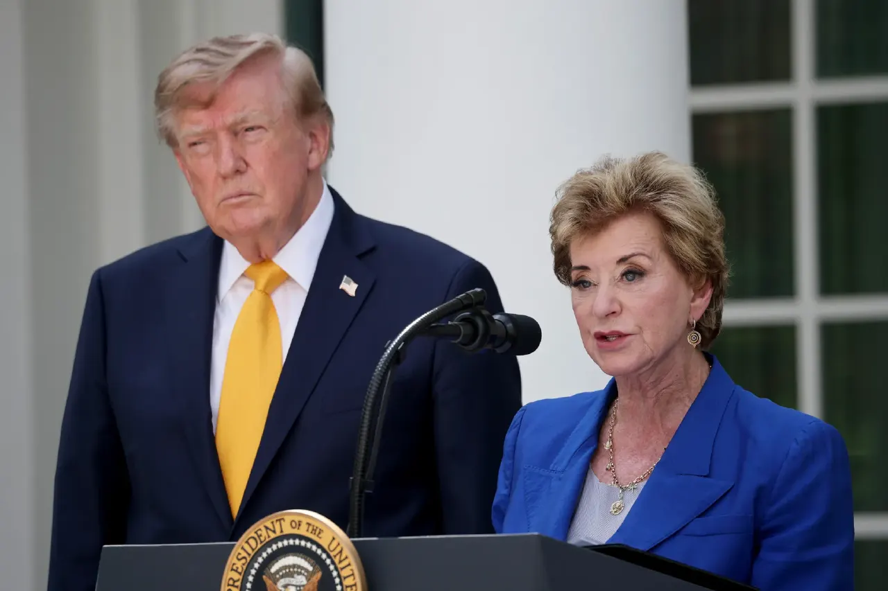 Two people at a podium with a presidential seal; one in navy suit, one speaking in blue jacket.