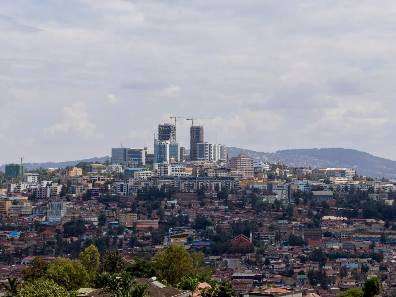 Wide view of a hillside city skyline with high-rise towers and dense rooftops.