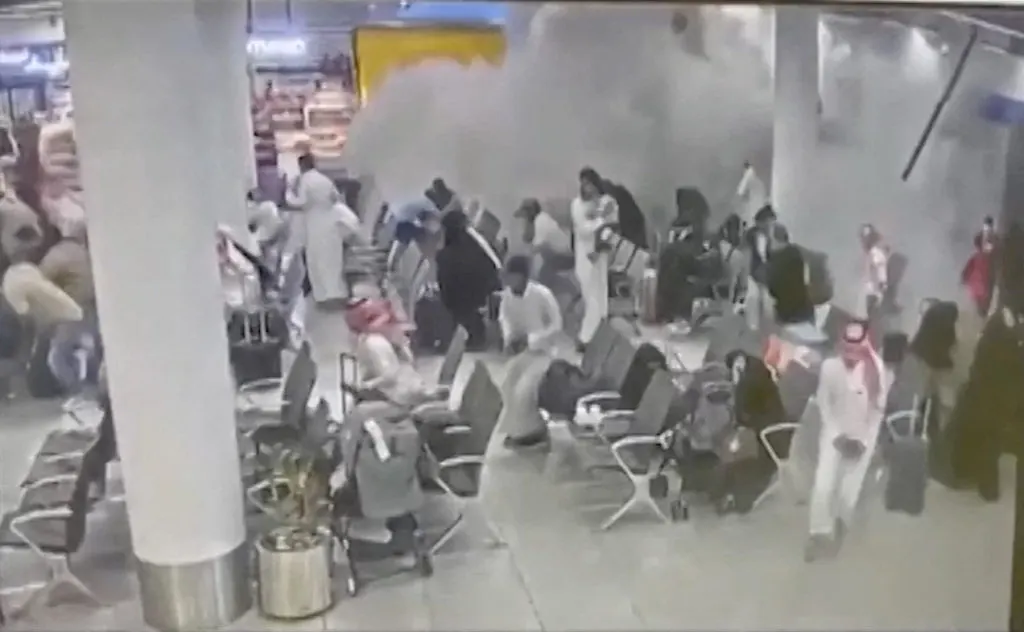 Grainy CCTV-style footage of smoke and panicked people in an airport waiting hall