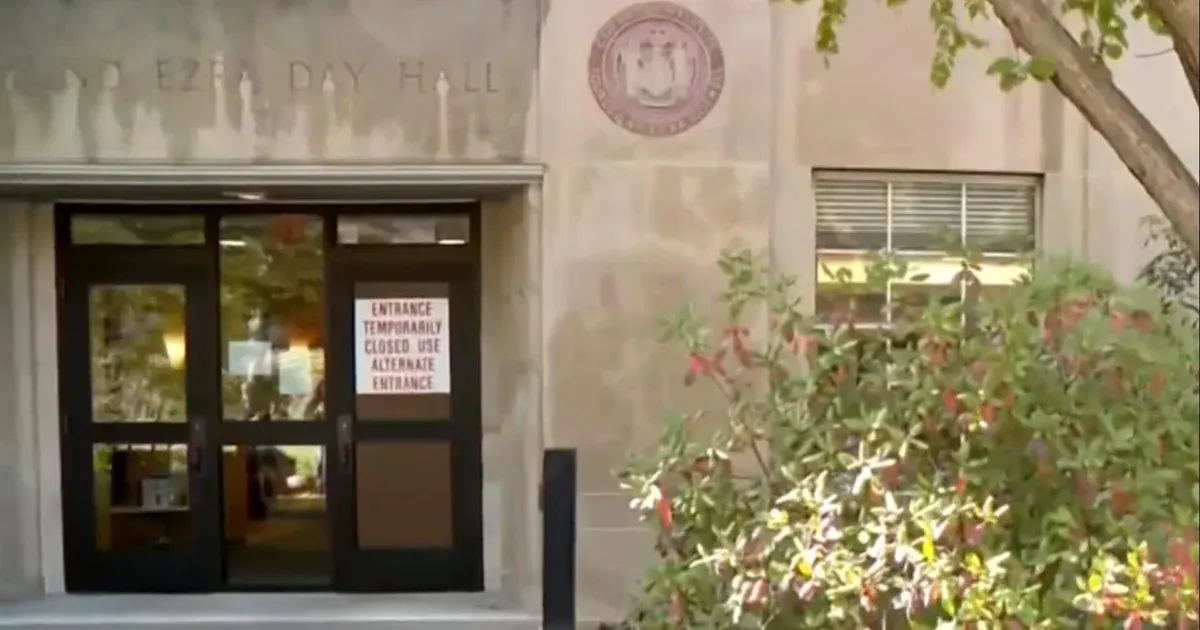 Entrance of a stone university hall with a sign reading temporarily closed, use alternate entrance.