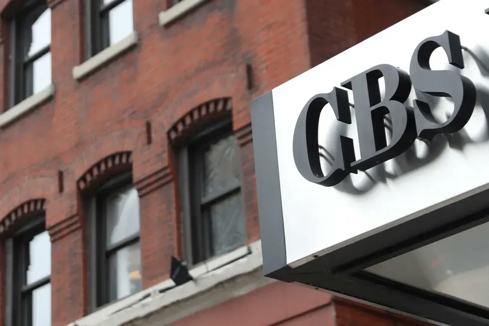 Black CBS lettering on a white sign above a brick building storefront facade.