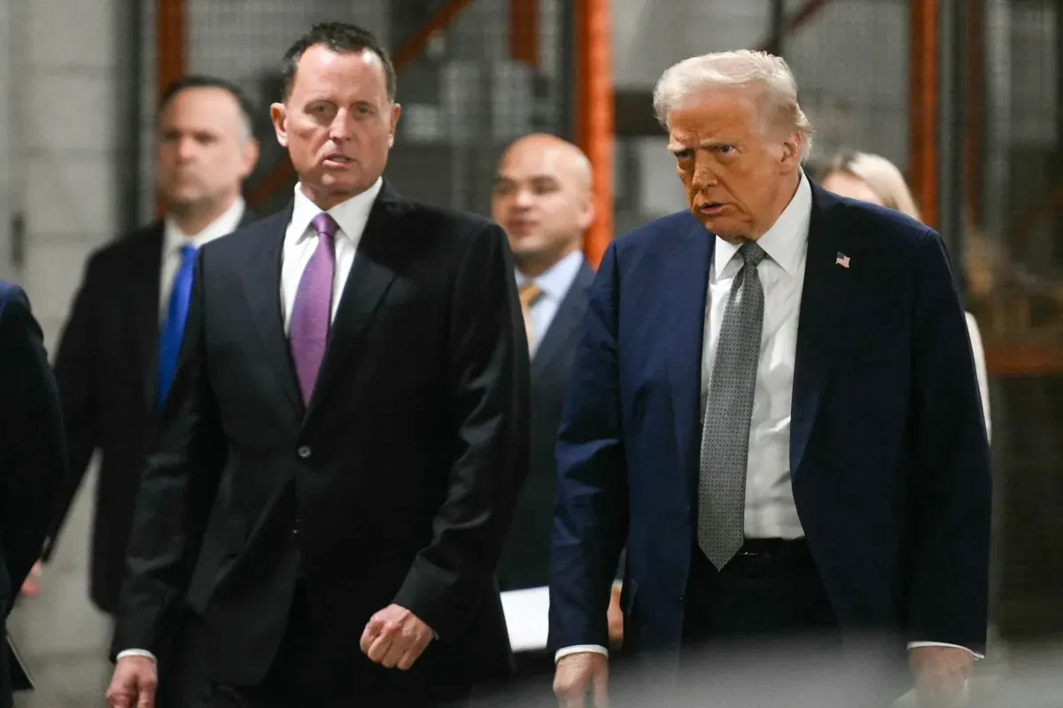 Men in dark suits walking together through an industrial warehouse corridor with orange racking.