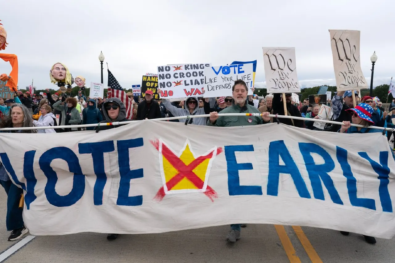 Marchers carry a large VOTE EARLY banner and protest signs reading No Kings, Vote, We the People, plus American flags.