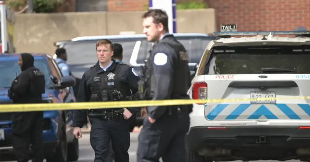 Uniformed police officers behind yellow tape beside a police SUV on a street.