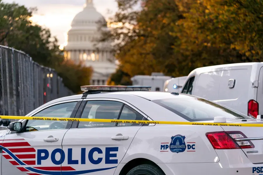 Police cruiser behind yellow police tape with the Capitol dome in background