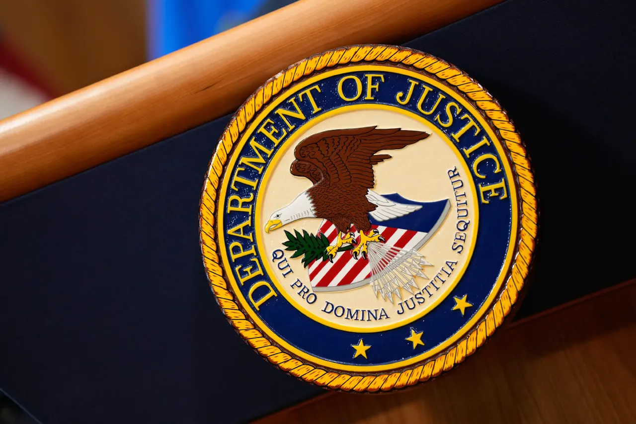 Department of Justice seal mounted on a wooden podium with dark blue panel