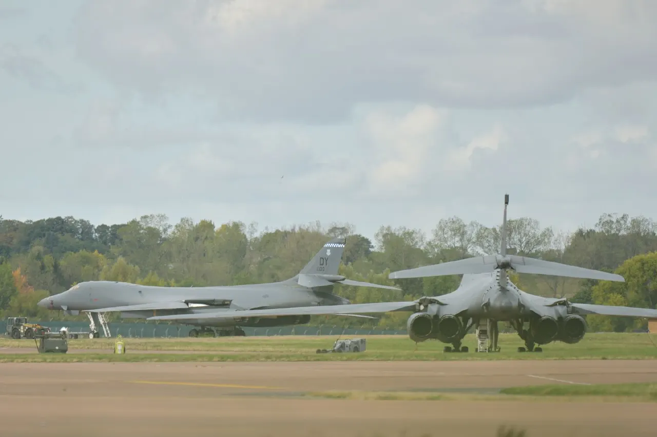 Military aircraft on airfield with personnel and vehicles nearby.