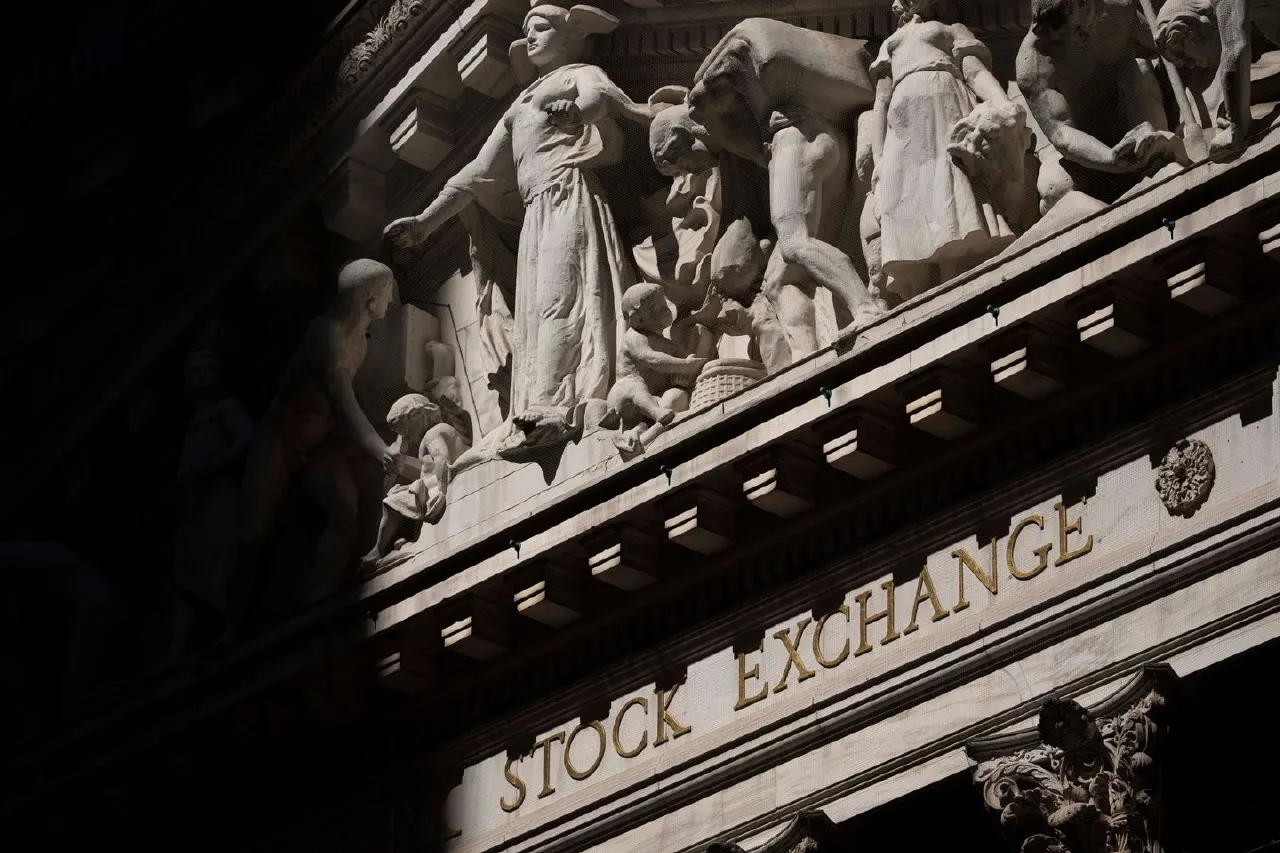 Carved stone sculptures and 'STOCK EXCHANGE' lettering on a building facade, shot from below.