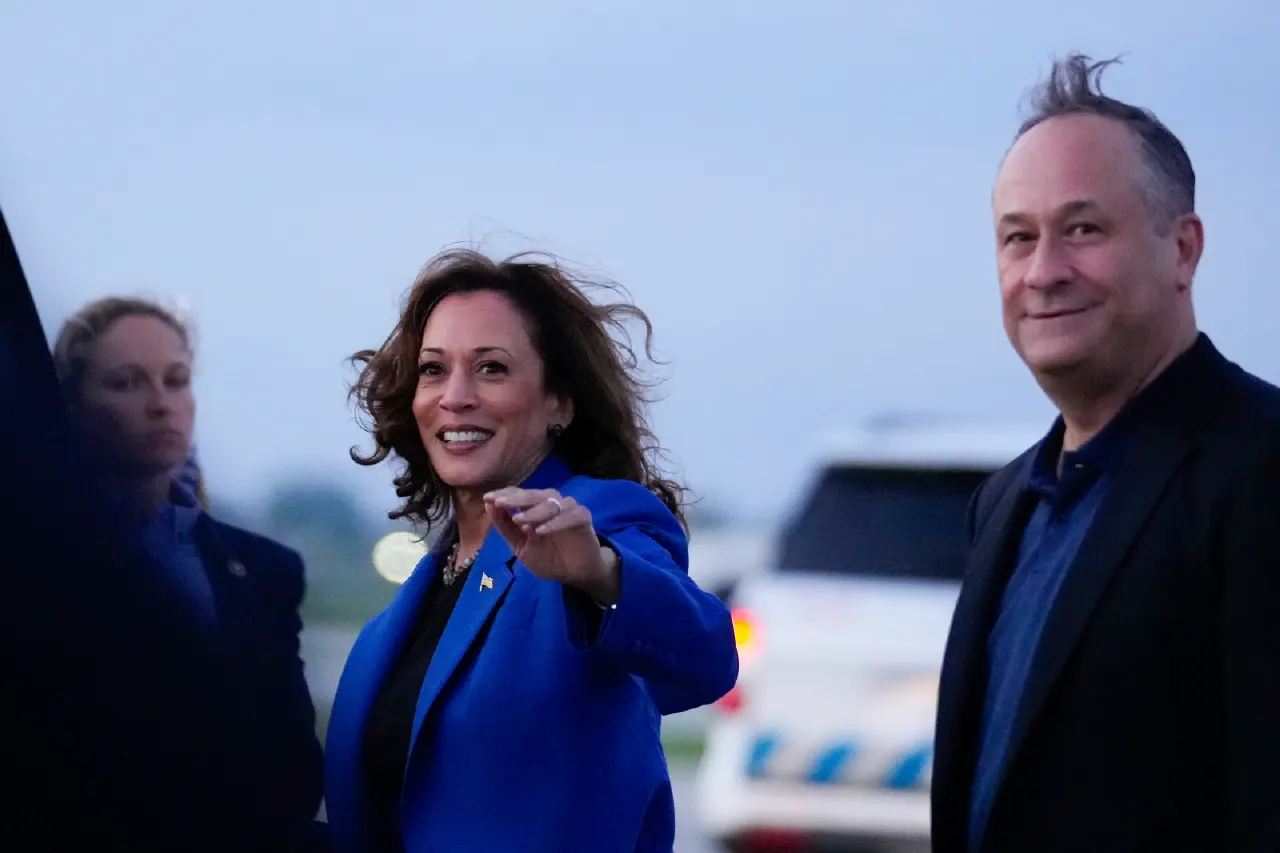 Smiling woman in bright blue blazer pointing, with a man in dark jacket at dusk