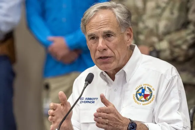 Gray-haired man in white Texas Division of Emergency Management shirt speaking at a microphone.