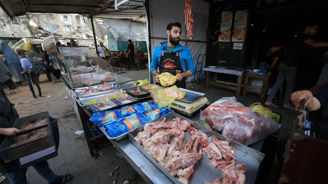 Street meat stall in Gaza with trays of raw meat and a vendor behind the counter.