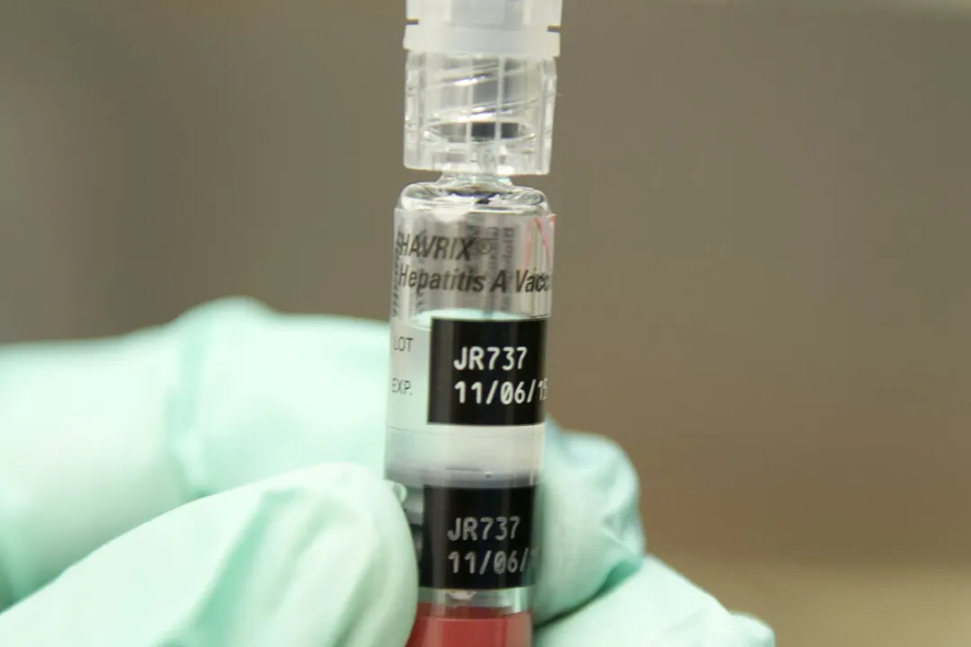 Gloved hand holding a Havrix Hepatitis A vaccine vial with lot label JR737.