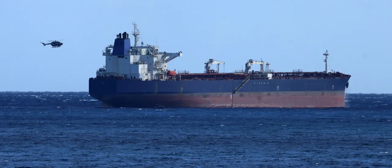 Large laden oil tanker at sea with a helicopter flying overhead on a clear day