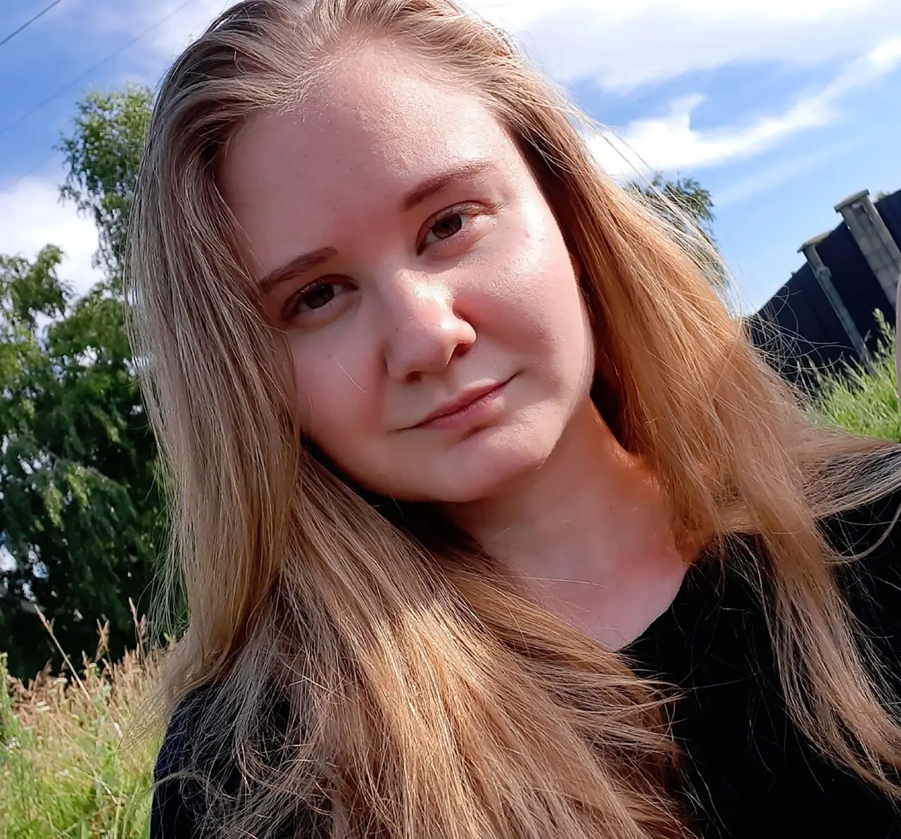 Portrait of a young woman with long reddish-brown hair outdoors