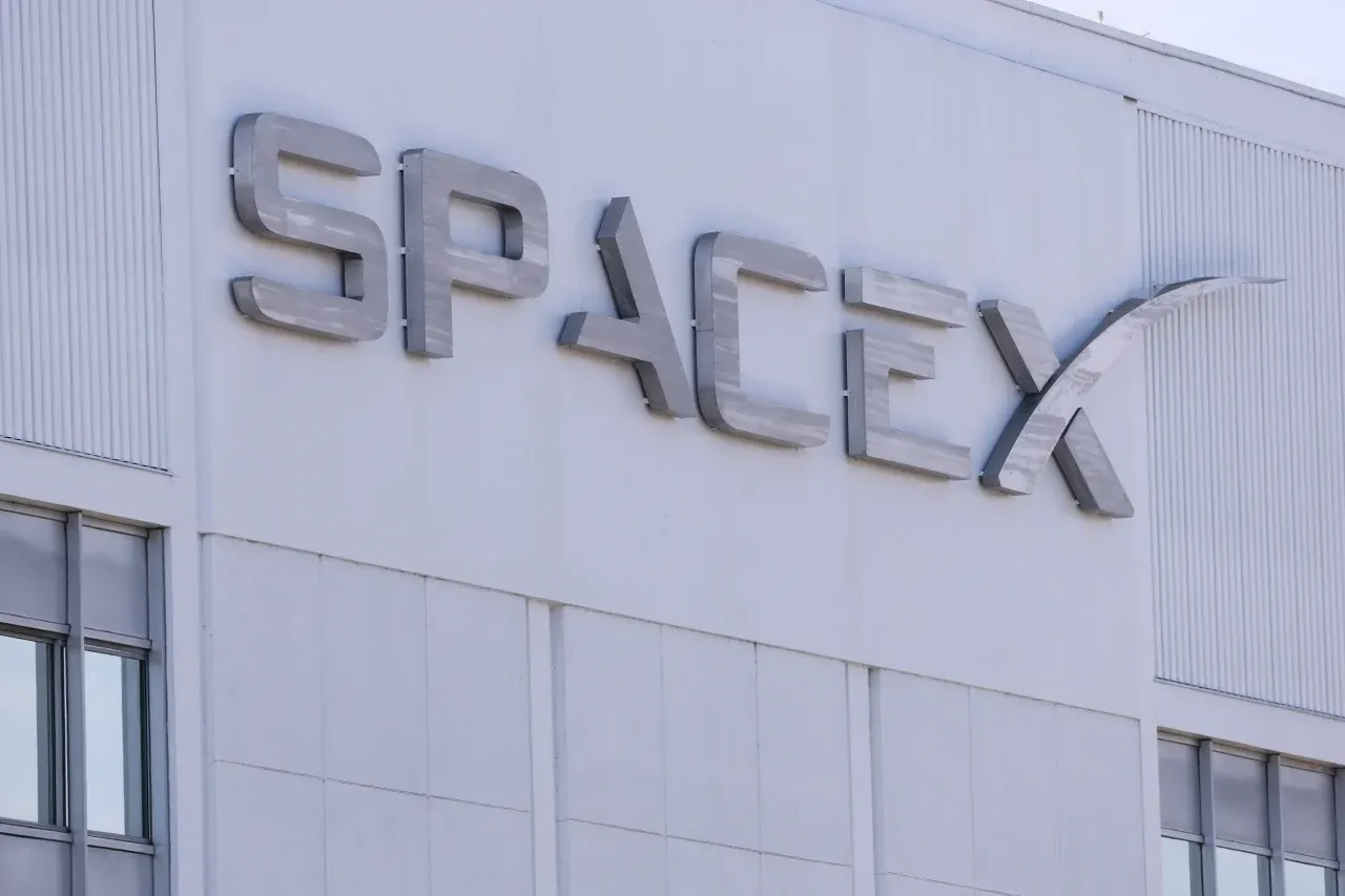 Metal SpaceX lettering mounted on a white building facade with windows