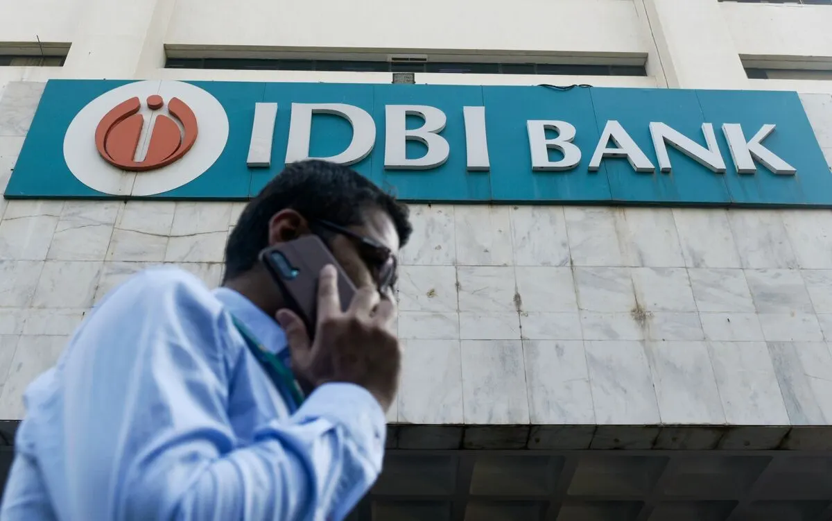 Man in glasses on phone walking past IDBI Bank sign and logo on building facade