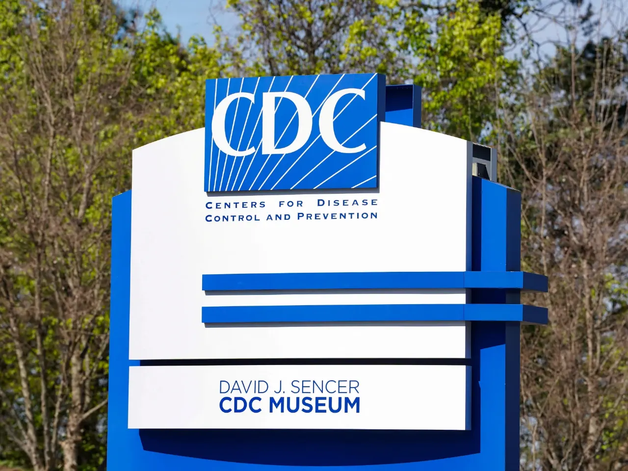 CDC logo and Centers for Disease Control and Prevention sign on a blue-and-white pylon outdoors.