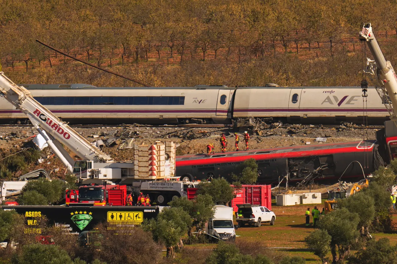 Derailed AVE high-speed train and red train wreckage with cranes and rescue workers at the crash site