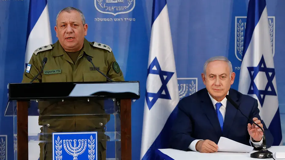 Uniformed officer speaks at podium beside seated man at press event before Israeli flags and emblems