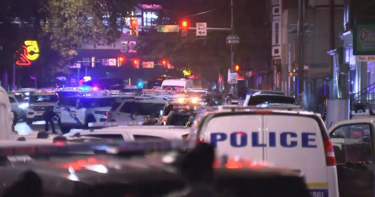 Night street scene with many police vehicles, flashing lights, and a van marked POLICE.