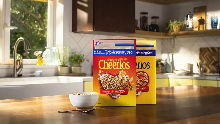 Two Honey Nut Cheerios boxes with Ziploc PantrySeal bag branding on a kitchen counter with a bowl of cereal.