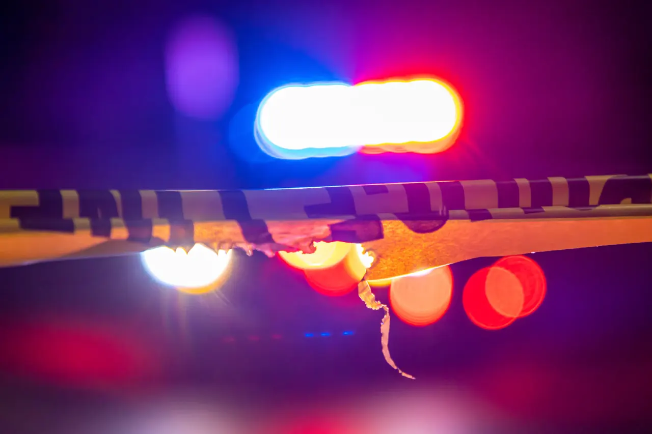 Blurred police lights behind yellow and black crime scene tape at night