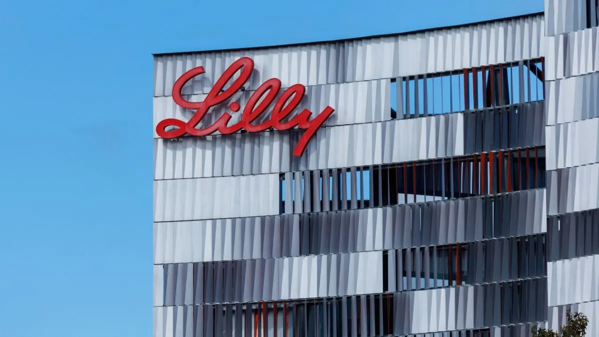 Red Lilly script logo mounted on a modern building facade against a blue sky.