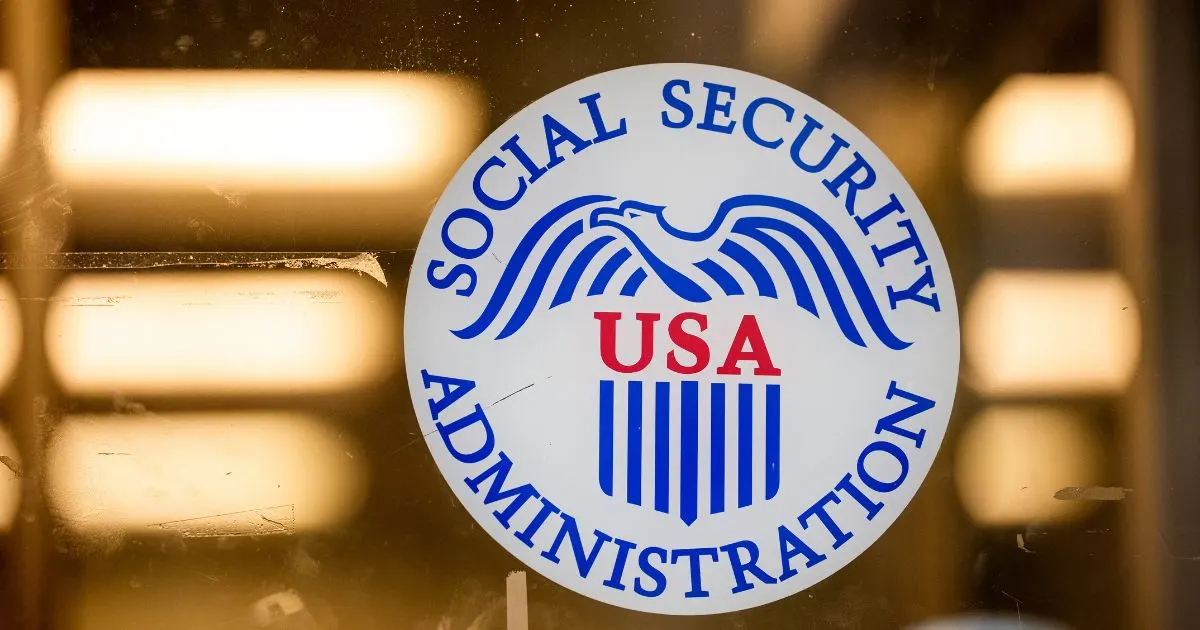 Social Security Administration seal with eagle and USA shield on a glass door, blurred warm lights behind.