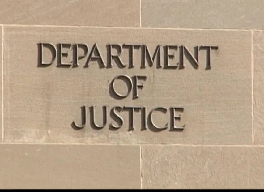 Carved stone sign reading Department of Justice on a building facade.