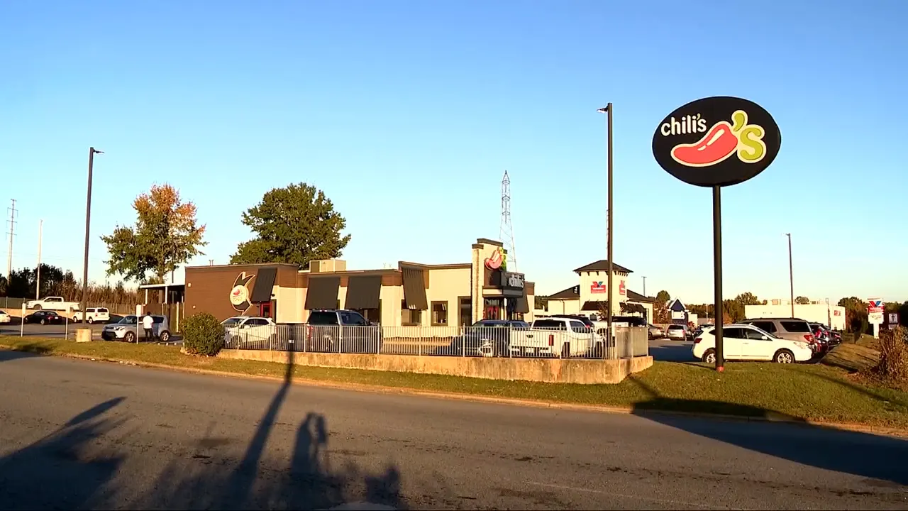 Chili's restaurant exterior with large illuminated Chili's sign in a parking lot, daytime.