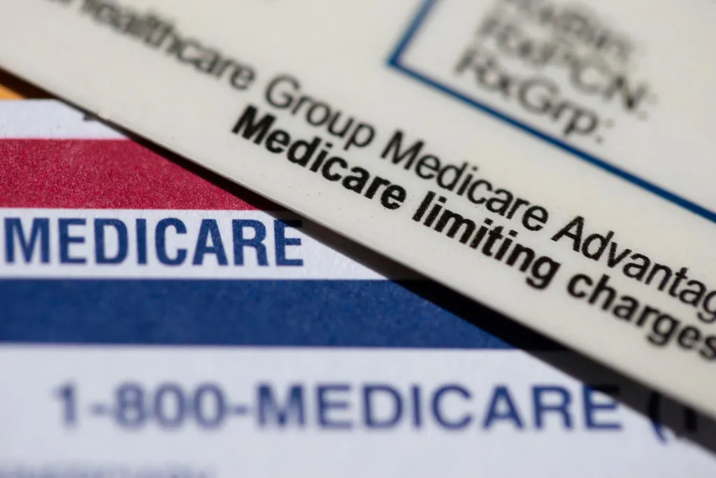 Close-up of Medicare cards and a Medicare Advantage group plan card with 'Medicare limiting charges' text.