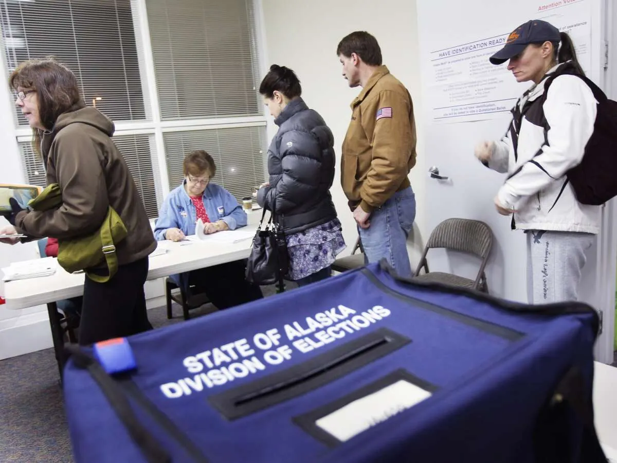 Voters checking in at a polling place beside a blue State of Alaska Division of Elections ballot box.
