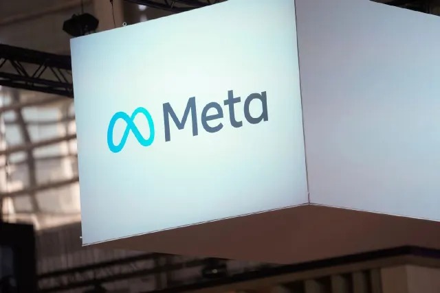 Illuminated hanging sign displaying the Meta logo in a building interior.