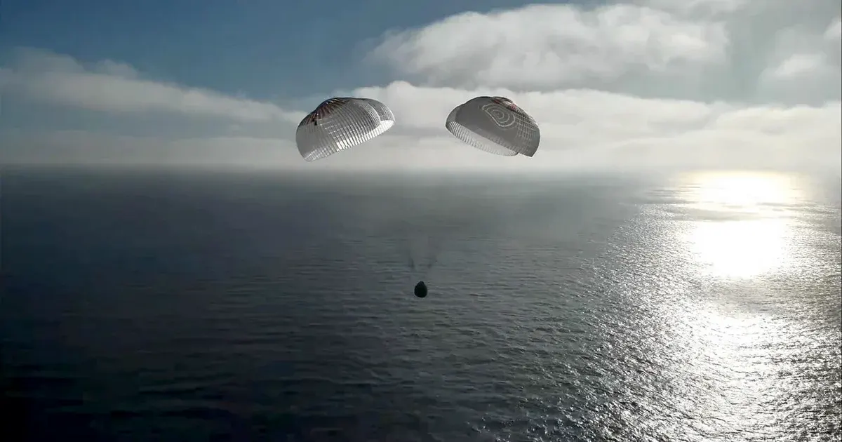 Capsule descending under two parachutes toward the ocean, seen from above, sunlit water.