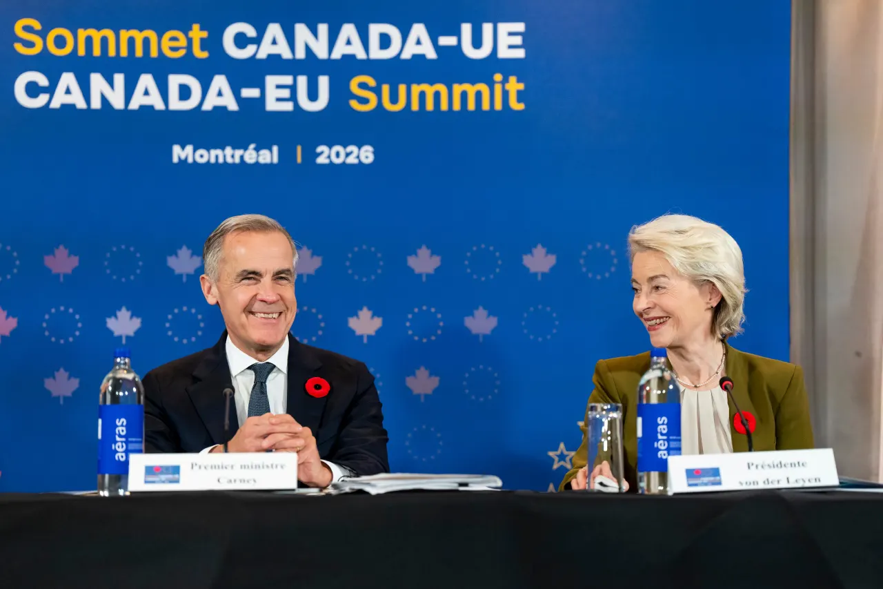 Two officials smile at a Canada-EU Summit Montreal 2026 panel table with name placards.