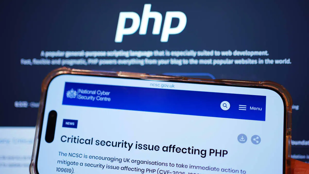 Phone showing NCSC security alert on PHP flaw, with PHP logo on screen behind